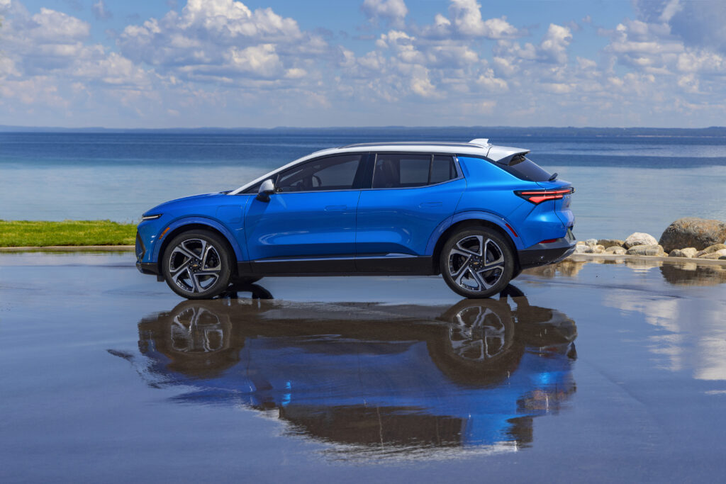 Driver’s side view of 2024 Chevrolet Equinox EV 3LT in Riptide Blue parked in front of a lake. Preproduction model shown. Actual production model may vary. 2024 Chevrolet Equinox EV available Fall 2023.